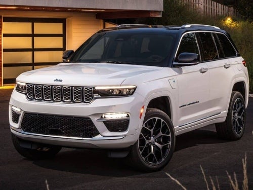 2024 Jeep Grand Cherokee parked outside a modern home at night